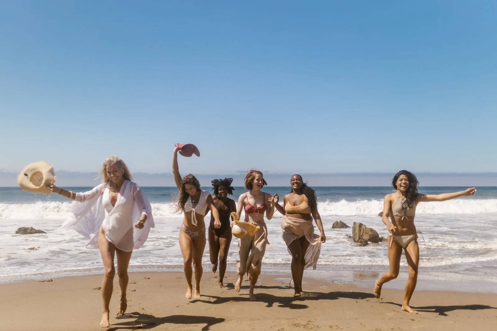 Vriendinnengroep op vakantie aan het rennen op strand 
